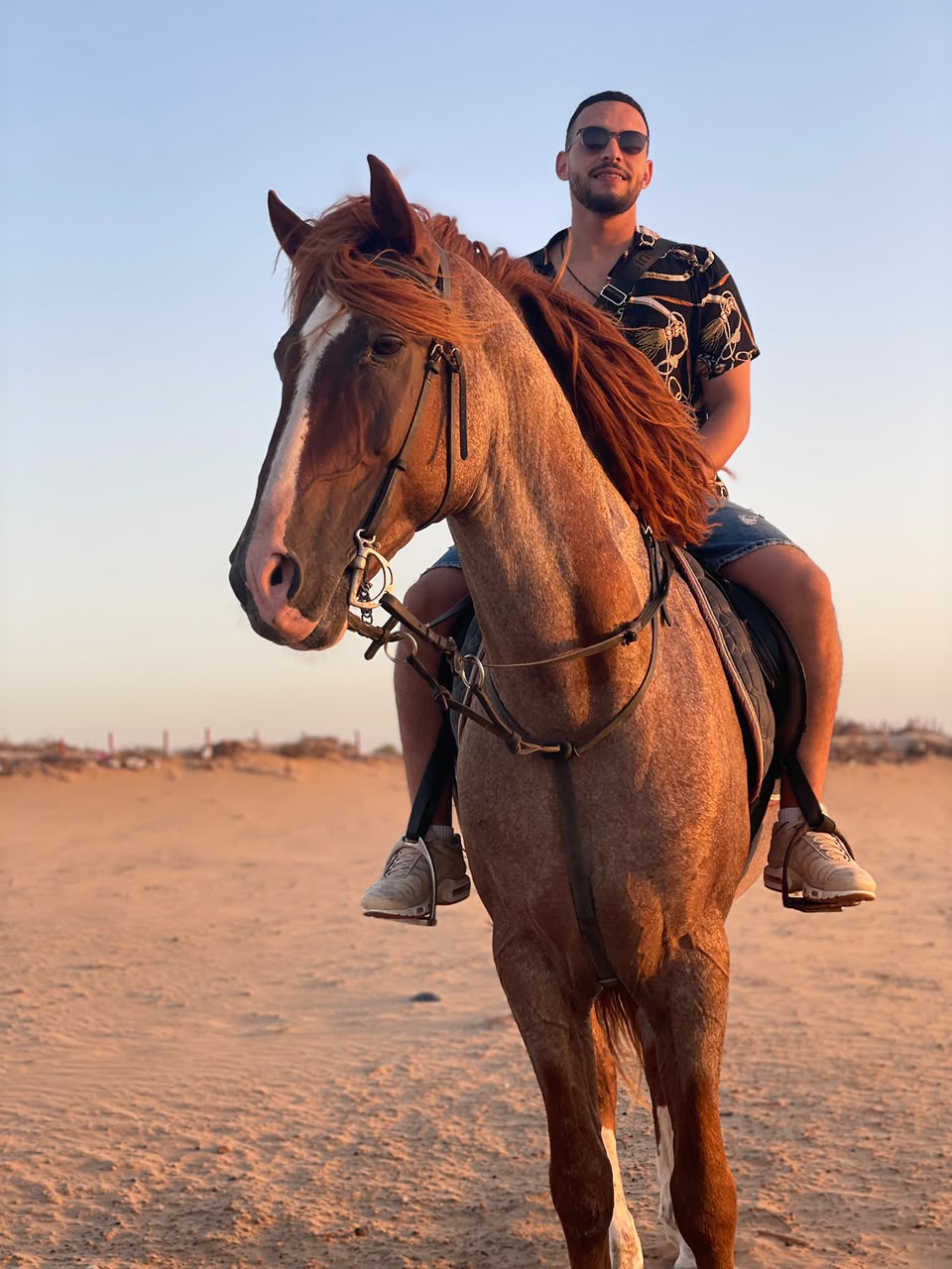 Marouane à cheval sur la plage au coucher du soleil, souriant